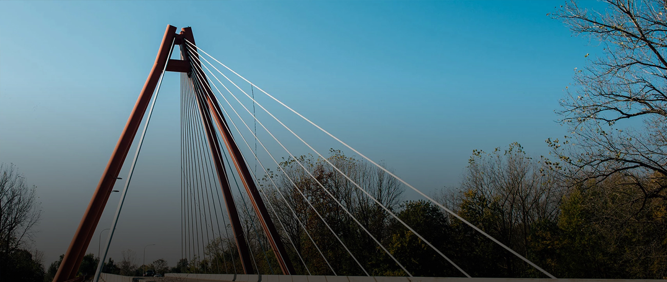 A photograph of a bridge in Indiana, the bridge is red and suspended by cables.